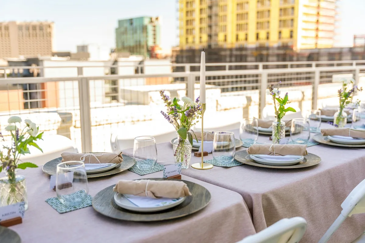 A dinner table set with plates, glasses, and flowers for guests