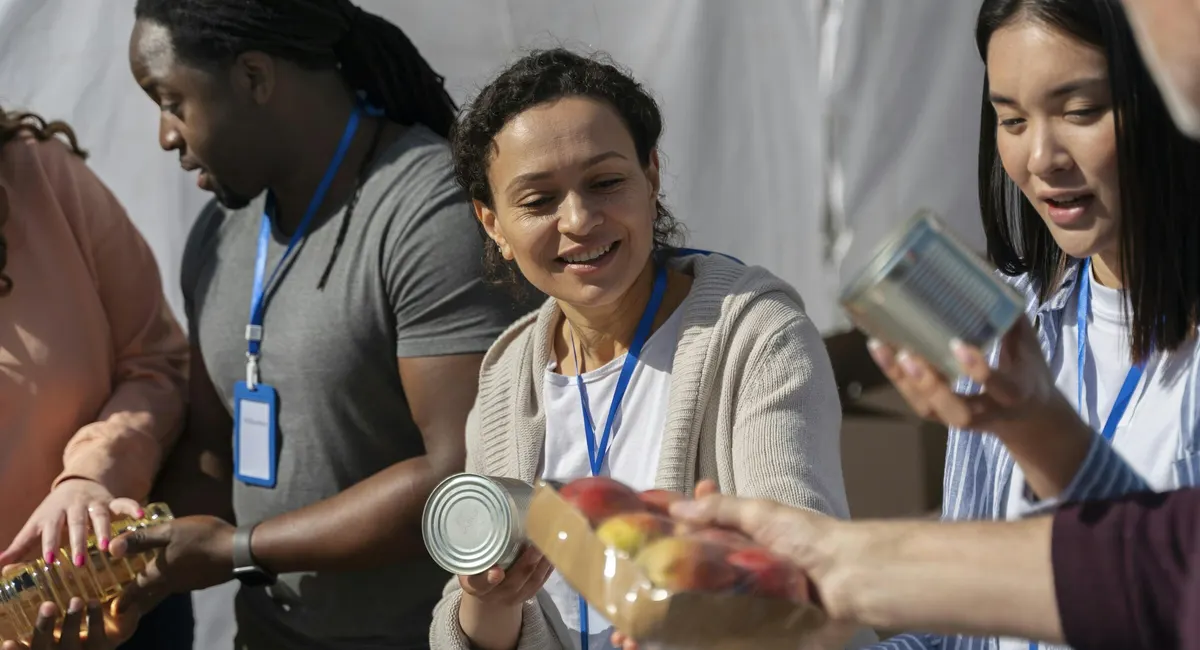 Volunteers wearing lanyards sort donated cans and food together at a food drive
