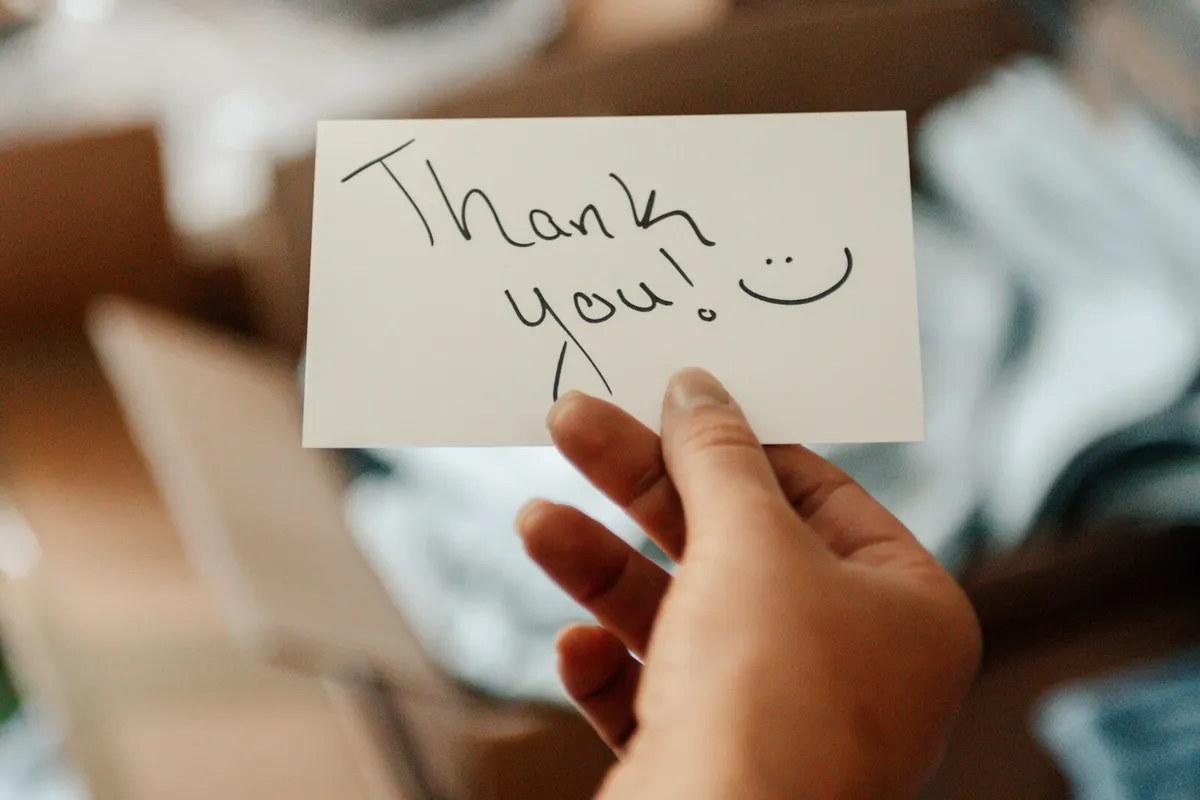 A hand holding a handwritten thank-you note